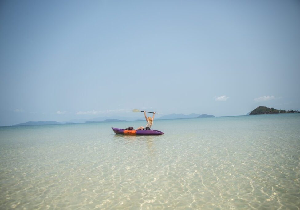 Person kayaking on clear turquoise water.