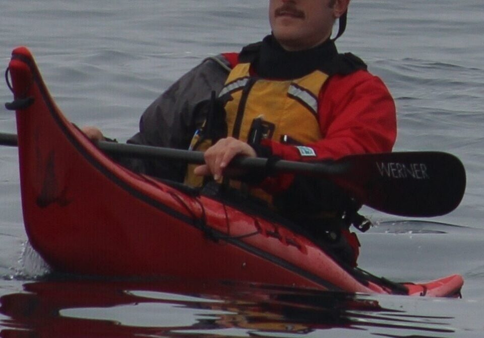 Person kayaking on calm water surface.